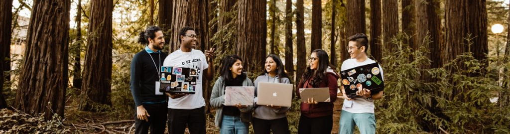 Students with laptop with redwoods behind them