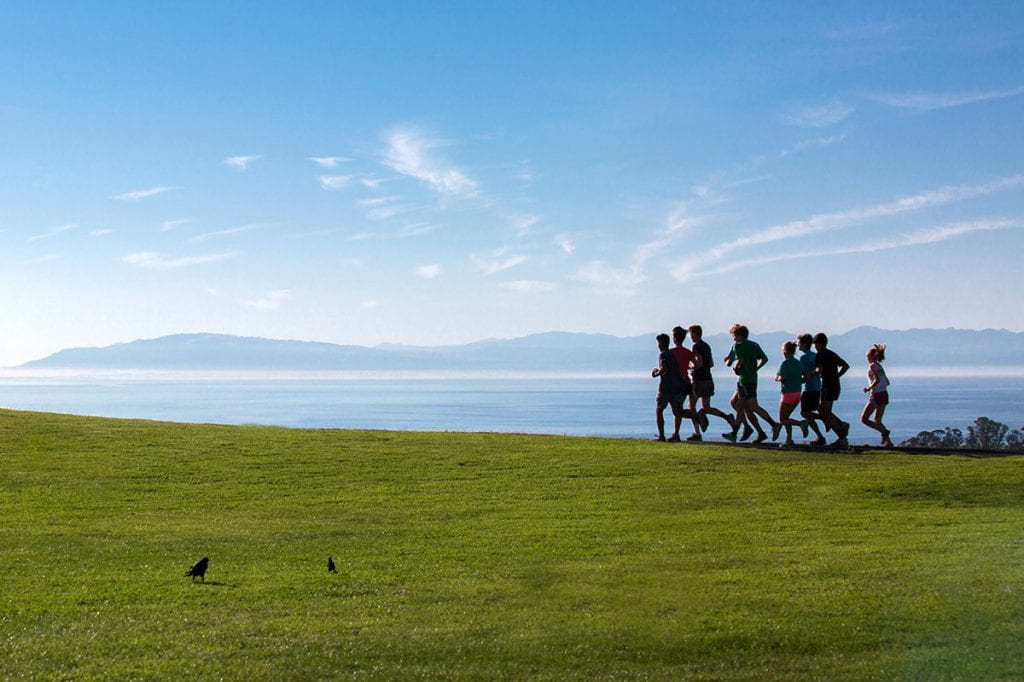 Students running on the Eastfield with Cruz Bay in the background